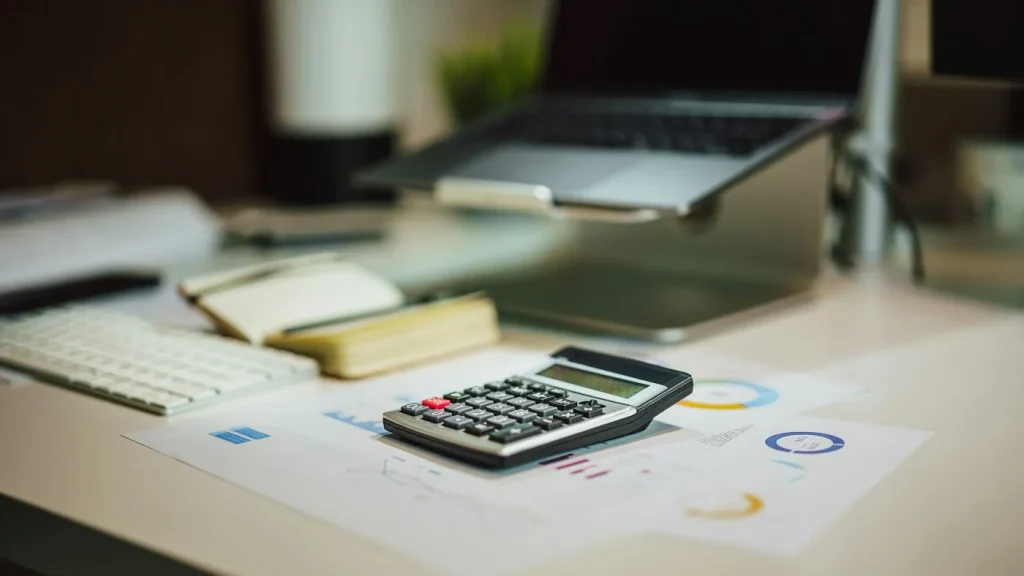 Calculator next to a laptop used for budget planning